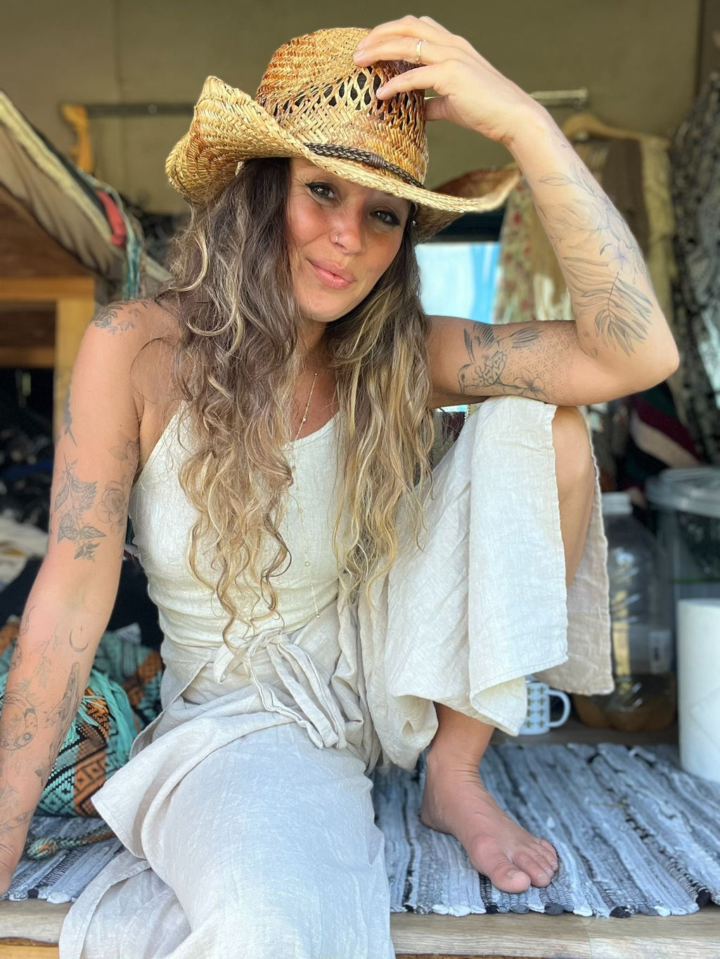 Woman wearing a straw hat and white dress sitting in van.